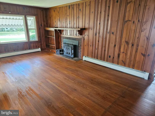 an empty room with wooden floor fireplace and windows