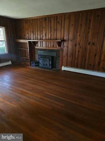 a view of empty room with wooden floor and fireplace