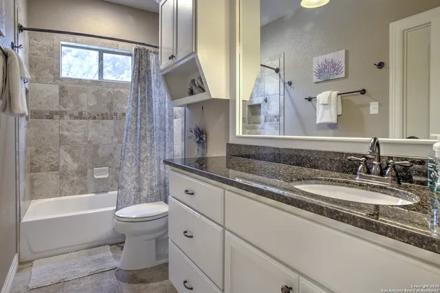 a bathroom with a granite countertop sink a toilet a mirror and bathtub