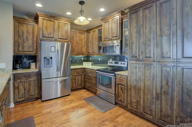 a kitchen with stainless steel appliances granite countertop a refrigerator a stove and a sink