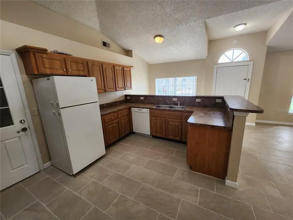 a kitchen with stainless steel appliances granite countertop a refrigerator a sink a stove a washer dryer and a refrigerator