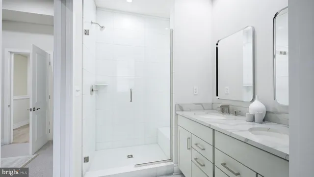 a bathroom with a granite countertop sink two mirror and shower