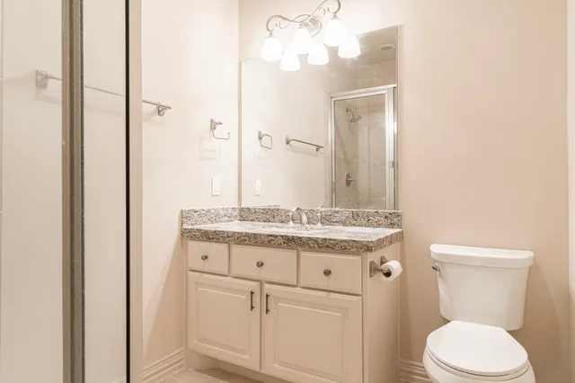 a bathroom with a granite countertop toilet sink and mirror