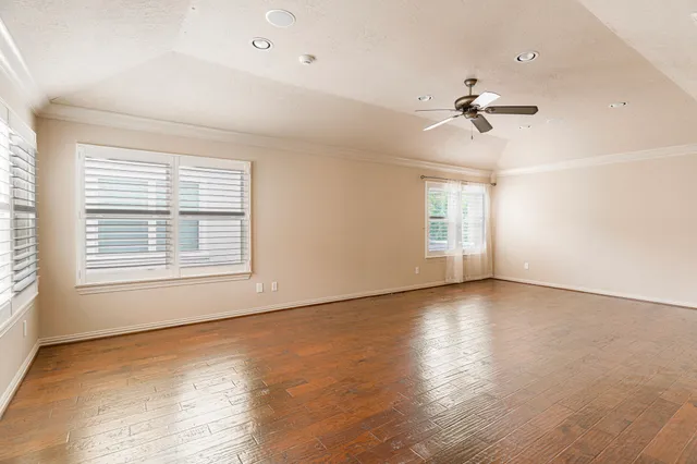 a view of empty room with wooden floor and fan