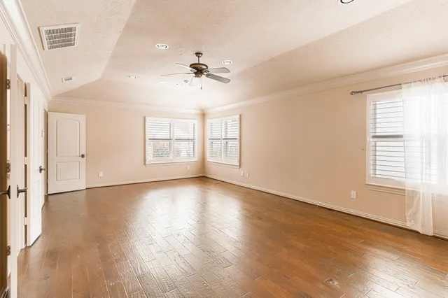 a view of an empty room with a window and wooden floor