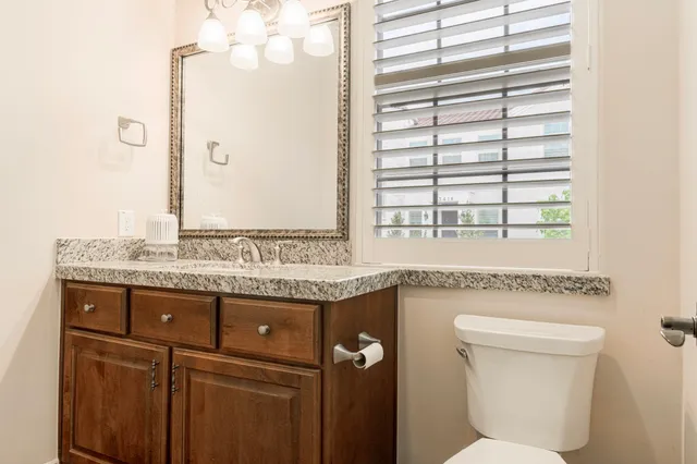 a bathroom with a granite countertop sink a toilet and a mirror