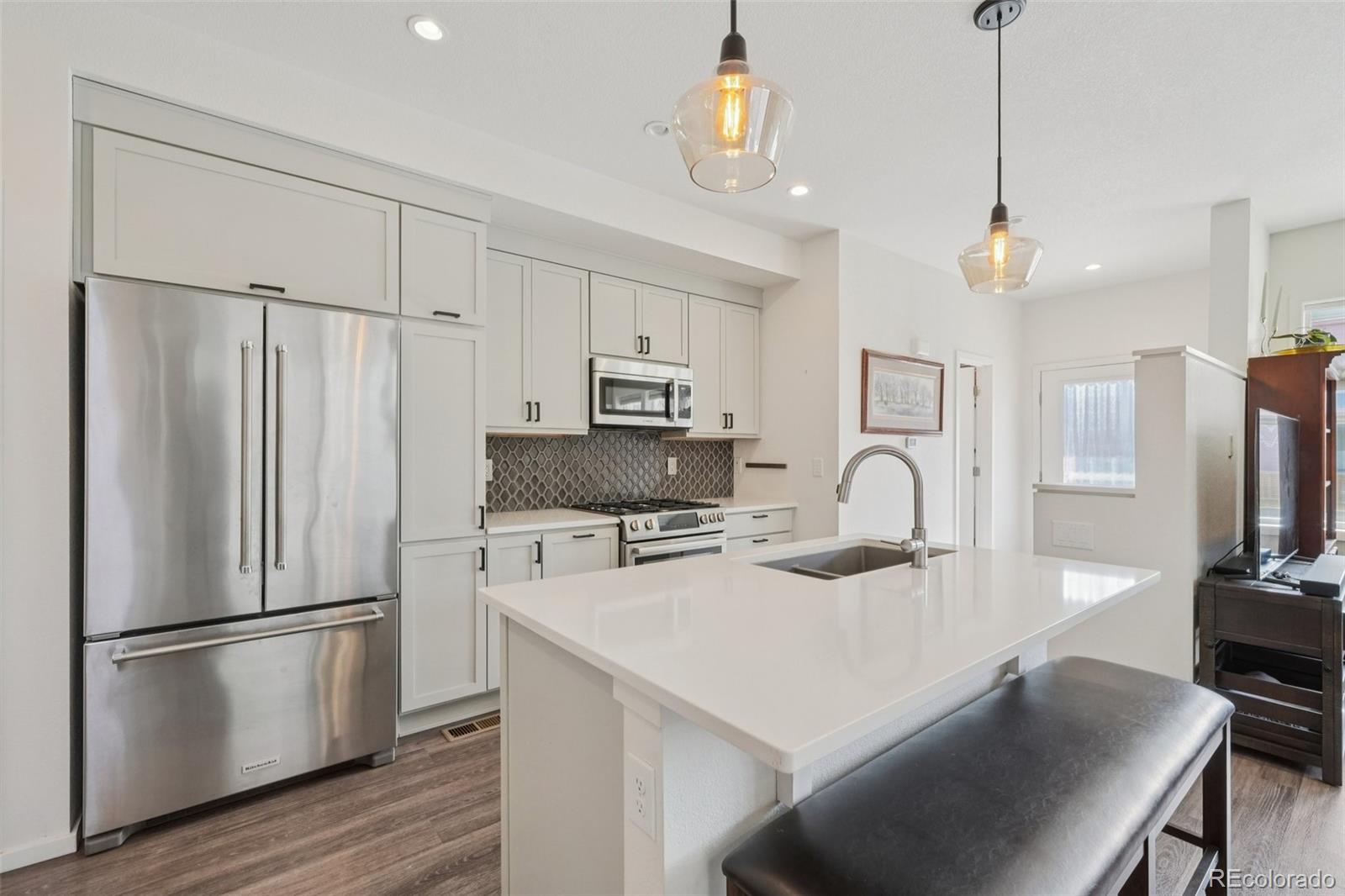 2005 West 66th Avenue Denver, CO 80221 - Photo 2 of 47 a kitchen with refrigerator a stove a dining table and chairs