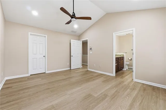 an empty room with wooden floor and a ceiling fan