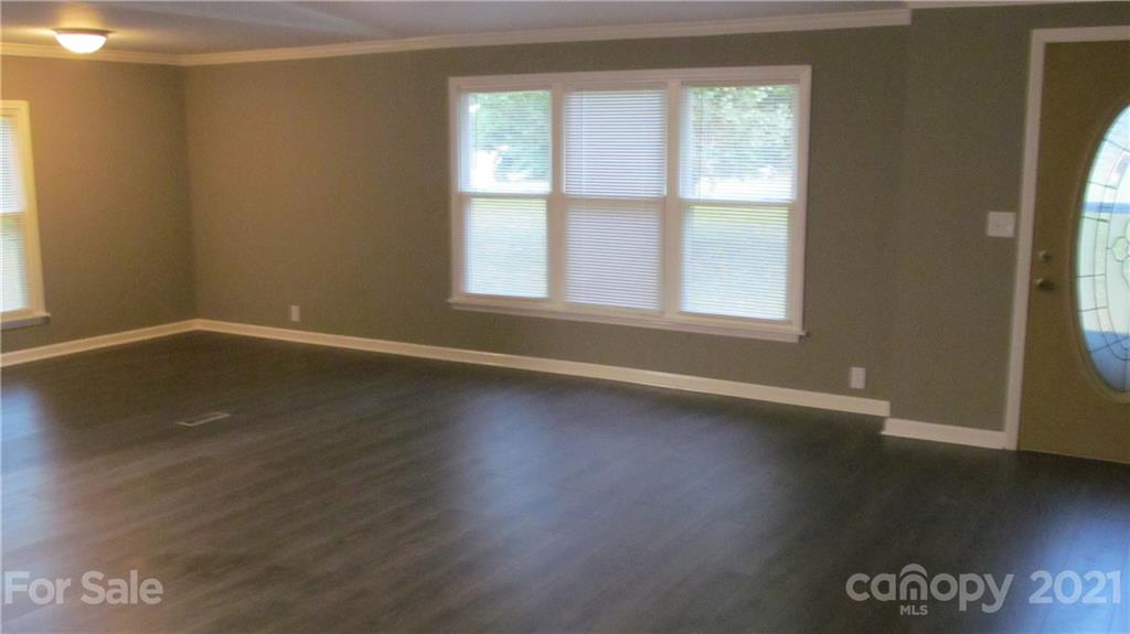 2896 Elbow Road Newton, NC 28658 - Photo 4 of 25 an empty room with wooden floor and windows with curtains