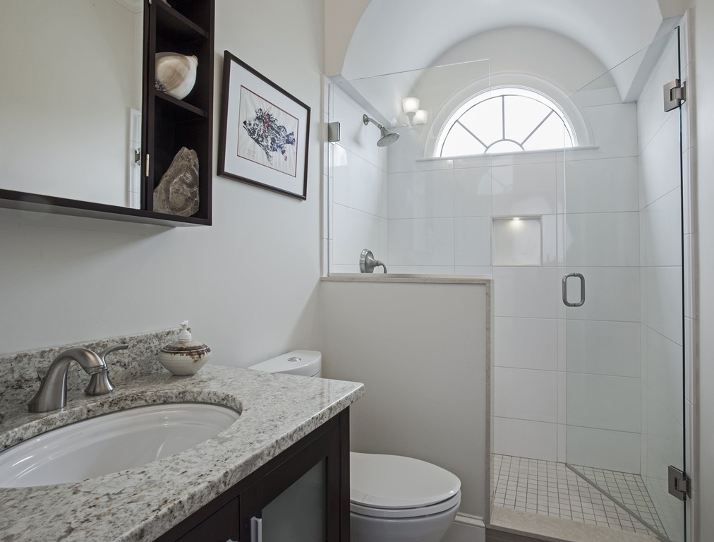 69 University Road, Unit 2 Brookline, MA 02445 - Photo 18 of 29 a bathroom with a granite countertop sink a toilet and a mirror