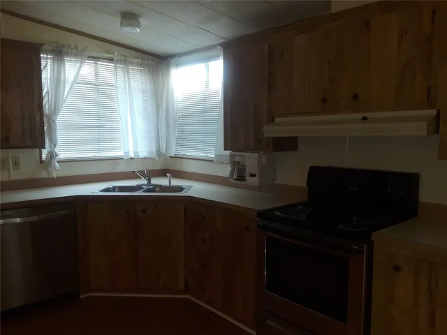 a kitchen with granite countertop a stove a sink and dishwasher with wooden floor