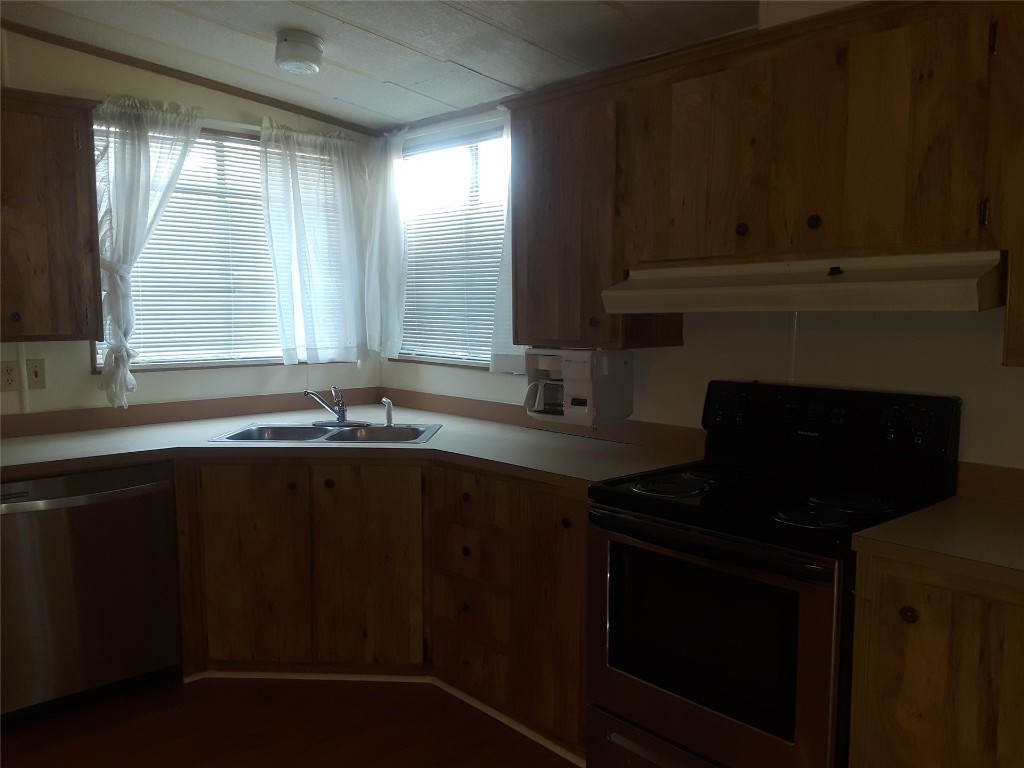 85112 Phillips Road Yulee, FL 32097 - Photo 2 of 17 a kitchen with granite countertop a stove a sink and dishwasher with wooden floor