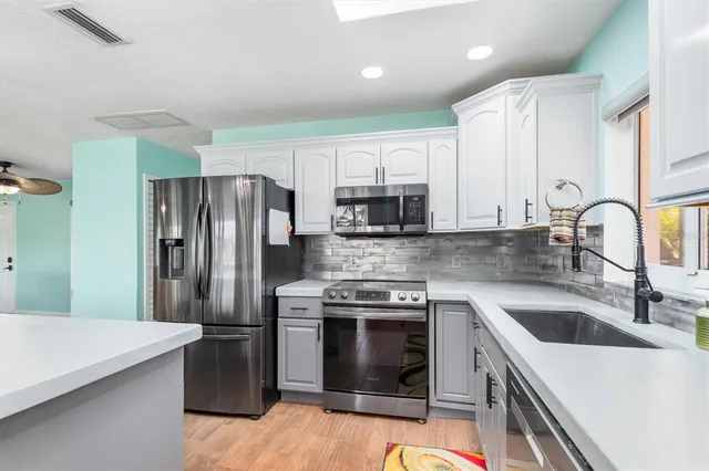 a kitchen with stainless steel appliances a stove refrigerator sink and microwave