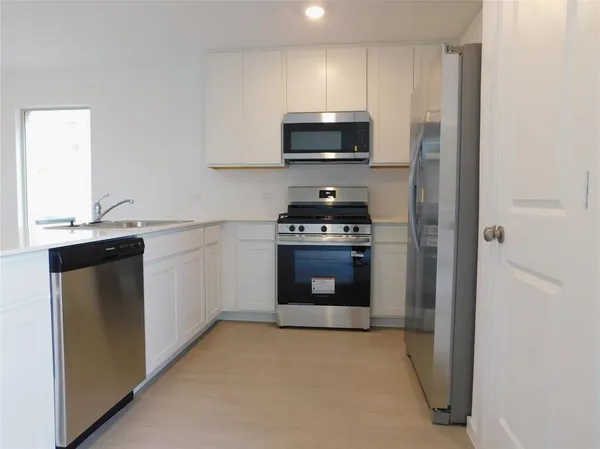 a kitchen with stainless steel appliances a stove a sink and a microwave