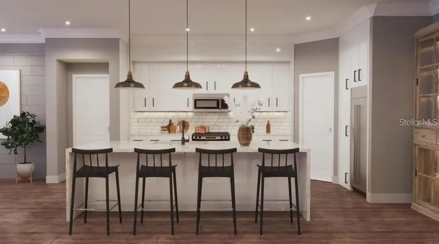 a kitchen with stainless steel appliances kitchen island granite countertop a table chairs and a refrigerator