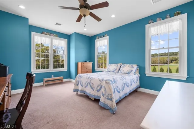 a spacious bedroom with a bed chandelier and windows