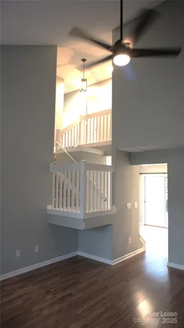 a view of a hallway to a big room with wooden floor and windows