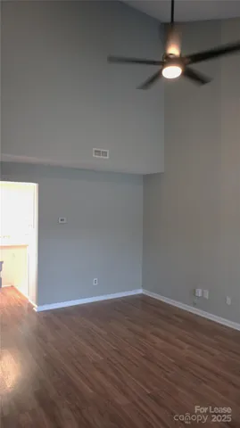 a view of an empty room with wooden floor fireplace and a window
