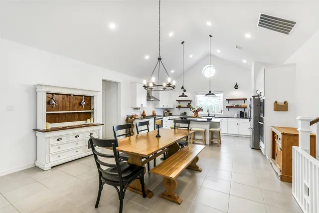 a kitchen with stainless steel appliances kitchen island granite countertop a stove a sink a dining table and chairs with wooden floor