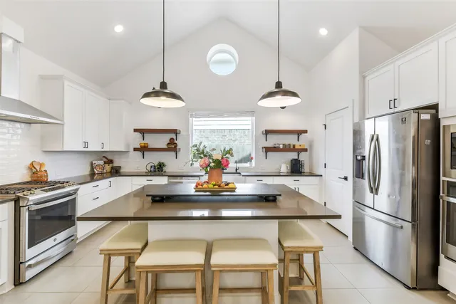 a kitchen with a dining table chairs stainless steel appliances and cabinets