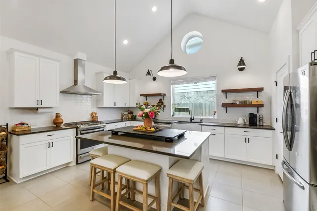 a kitchen with stainless steel appliances a stove a sink dishwasher a refrigerator and white cabinets with wooden floor