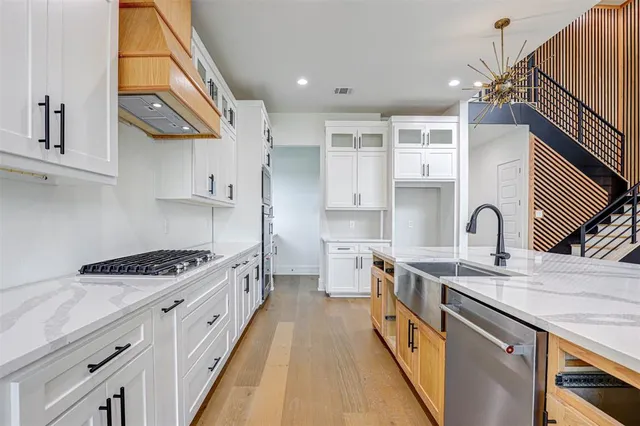 a kitchen with kitchen island stainless steel appliances a sink a stove and a wooden cabinets
