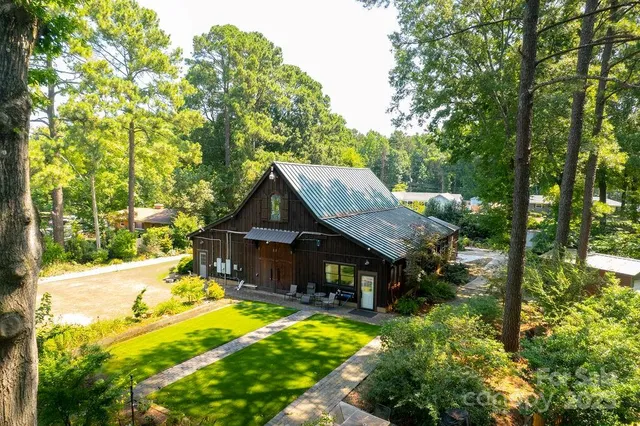 a view of a big house with large trees and plants