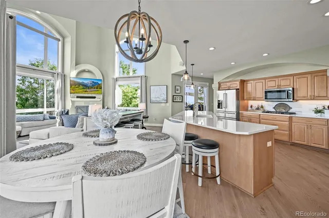 a dining room with wooden floor a chandelier a wooden table and chairs