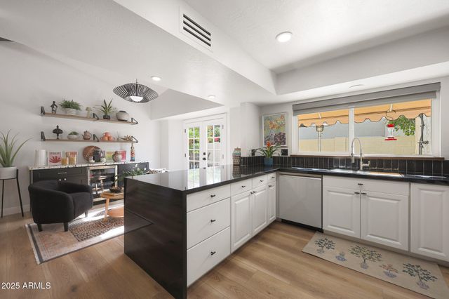 a kitchen with kitchen island granite countertop a stove top oven a sink dishwasher a refrigerator and white cabinets with wooden floor