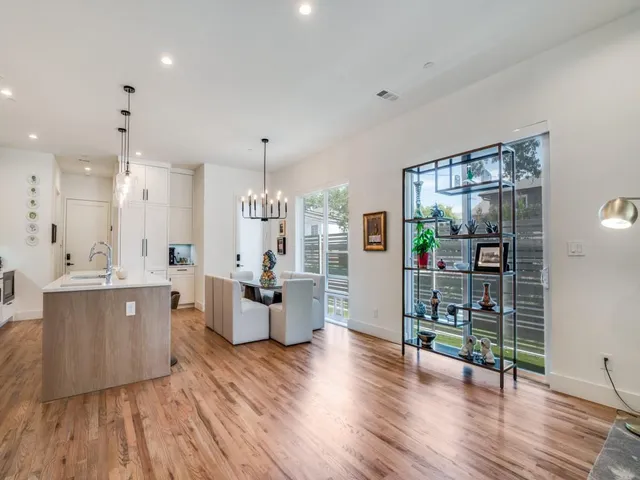 a large kitchen with stainless steel appliances a large counter top a wooden floors and a large window