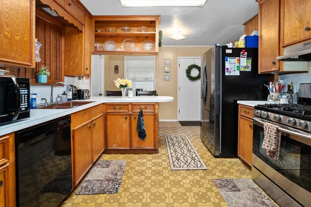 a kitchen with stainless steel appliances granite countertop a refrigerator a stove and a sink