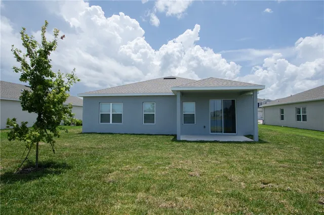 a view of a house with a yard and a large tree