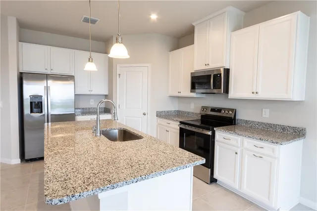 a kitchen with granite countertop a sink a counter top space stainless steel appliances and cabinets