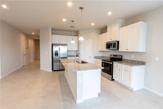 a large kitchen with kitchen island a sink a stove a microwave a center island and a refrigerator