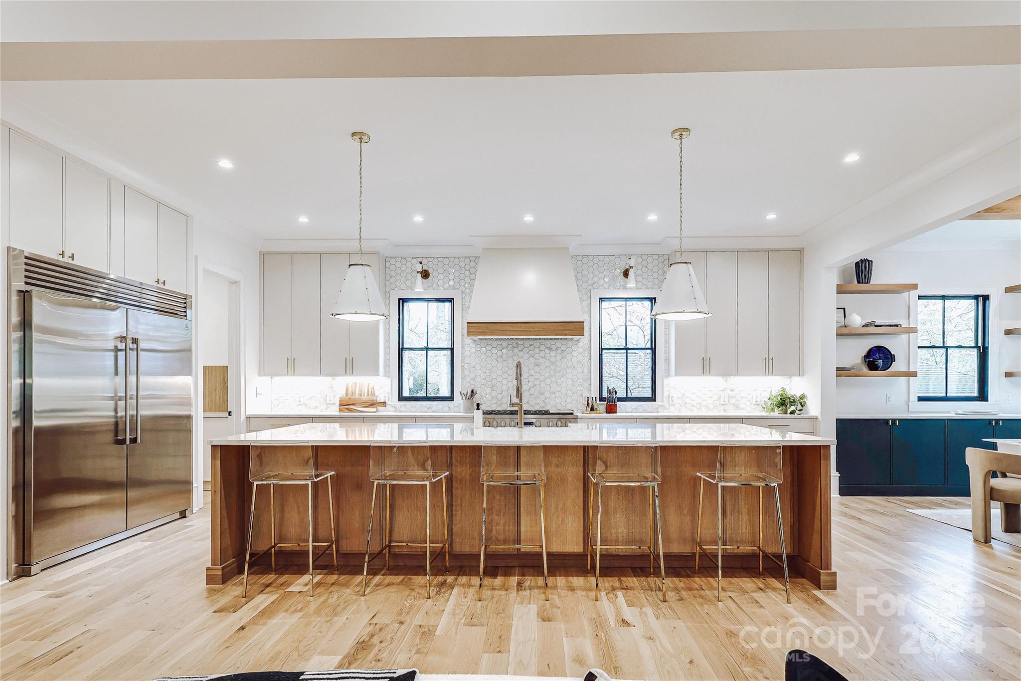 a kitchen with kitchen island stainless steel appliances a dining table chairs sink and cabinets