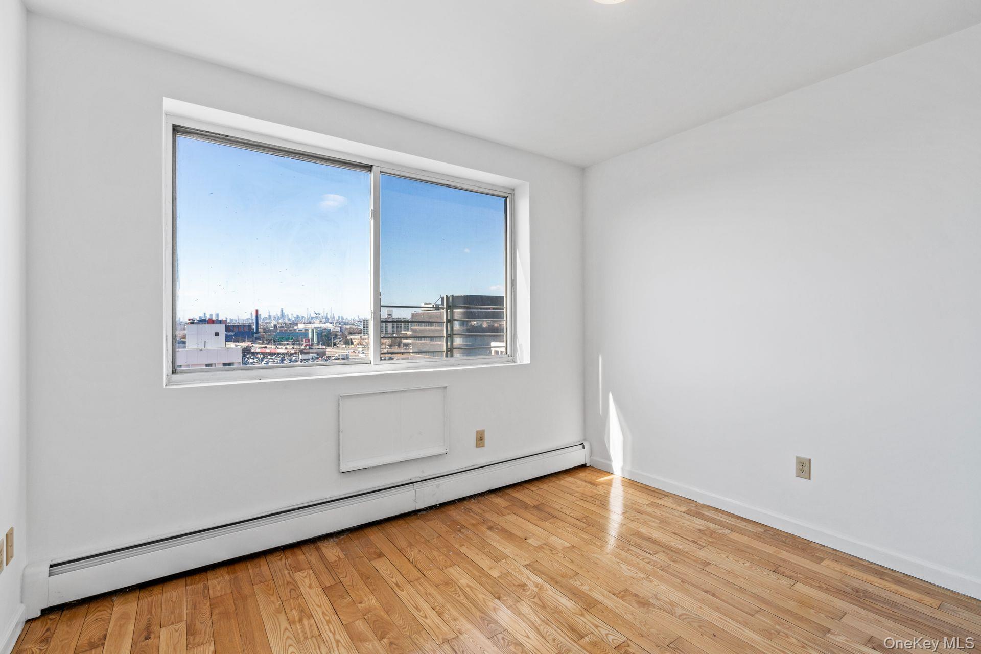 136-16 31st Road, Unit 8B Queens, NY 11354 - Photo 16 of 23 Unfurnished room featuring a baseboard radiator and light hardwood / wood-style floors