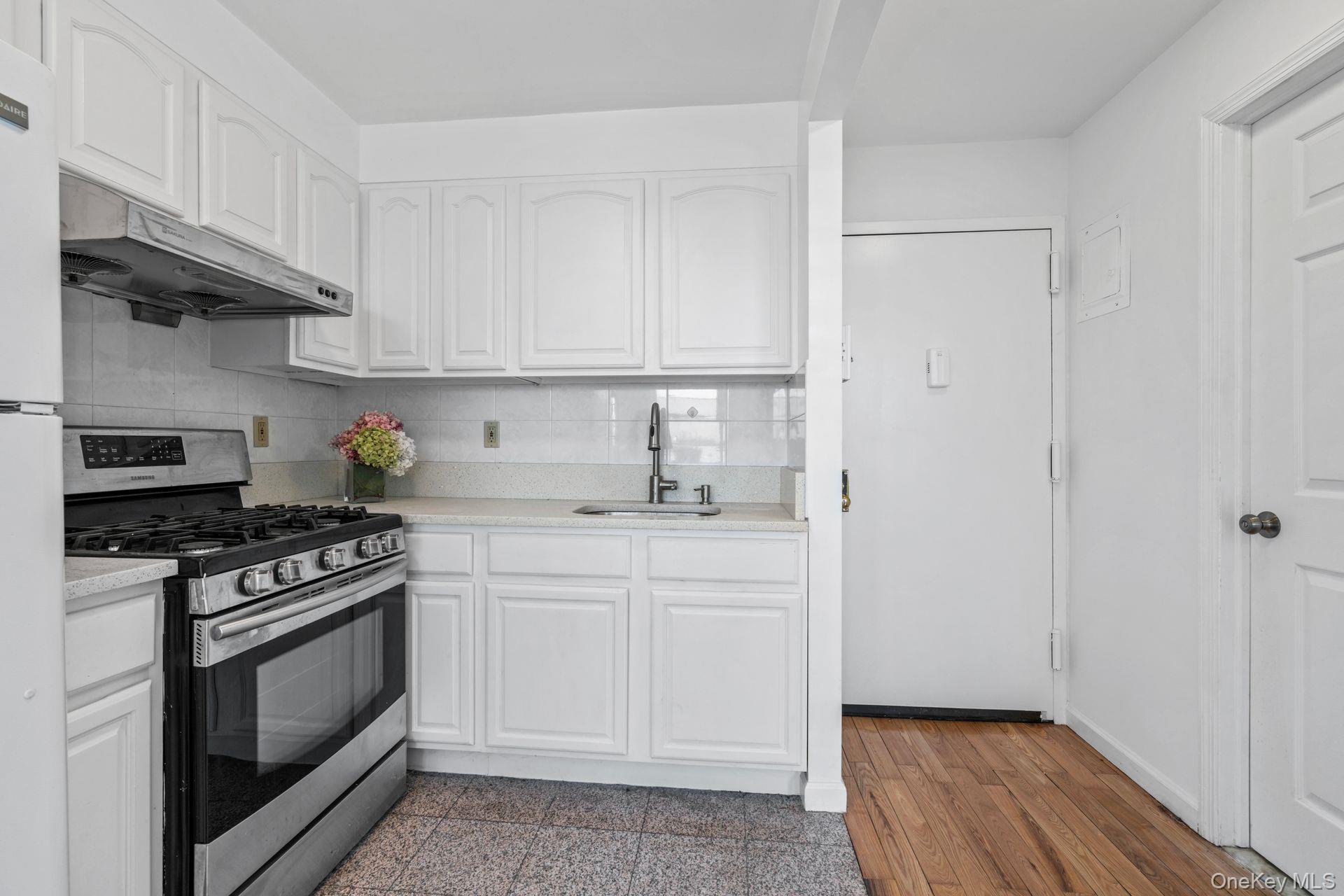 136-16 31st Road, Unit 8B Queens, NY 11354 - Photo 4 of 23 Kitchen with white cabinetry, sink, tasteful backsplash, and gas stove