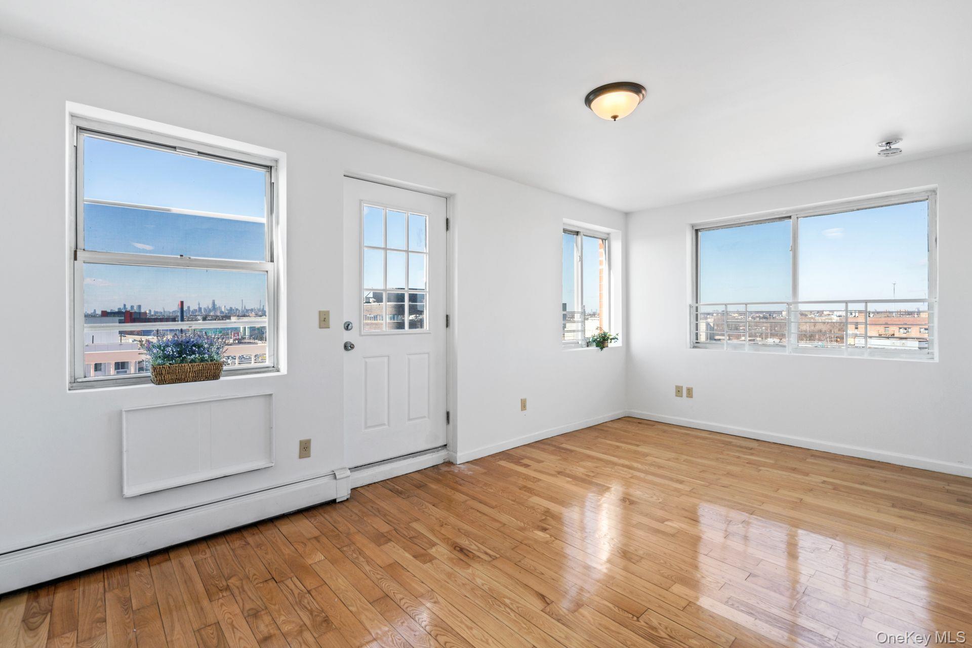 136-16 31st Road, Unit 8B Queens, NY 11354 - Photo 6 of 23 Foyer featuring a baseboard radiator, light hardwood / wood-style floors, and a healthy amount of sunlight