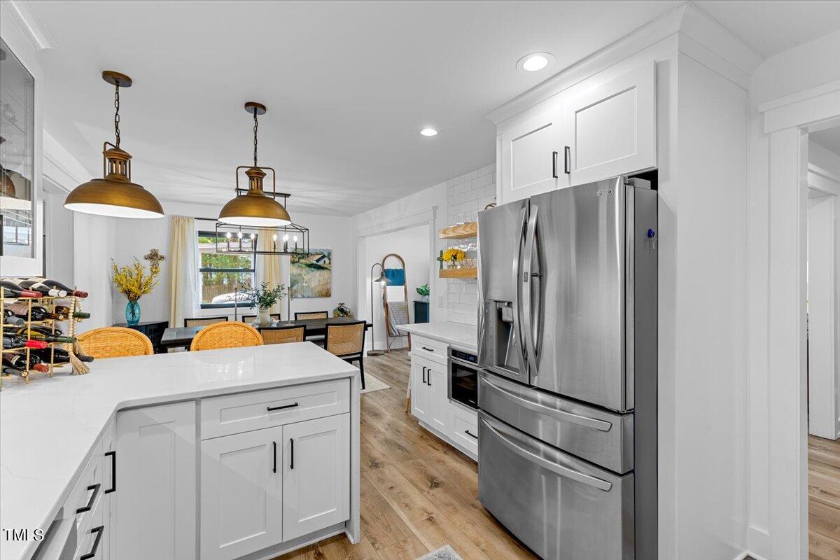 5700 Tully Court Raleigh, NC 27609 - Photo 12 of 26 a kitchen with stainless steel appliances a refrigerator a sink a stove and a wooden floors