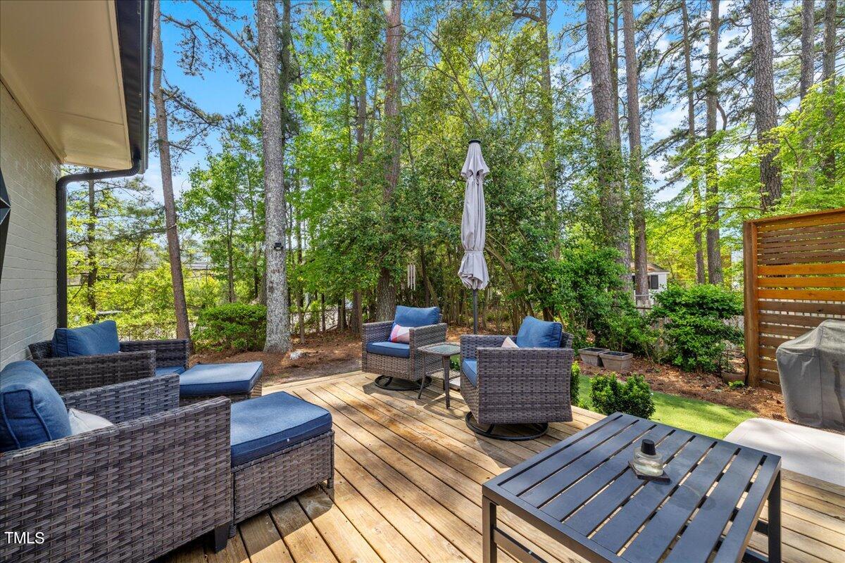 5700 Tully Court Raleigh, NC 27609 - Photo 25 of 26 a view of a deck with couches table and chairs with wooden floor and fence
