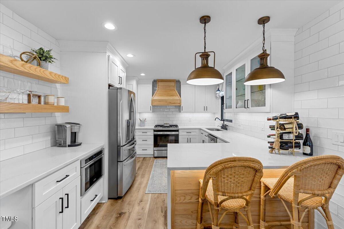 5700 Tully Court Raleigh, NC 27609 - Photo 10 of 26 a kitchen with stainless steel appliances granite countertop a sink a stove and chairs