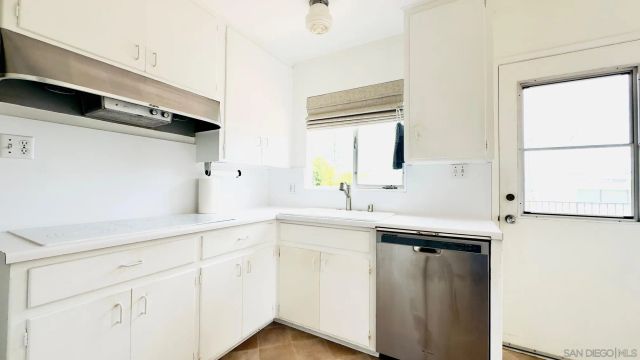 a kitchen with white cabinets and sink