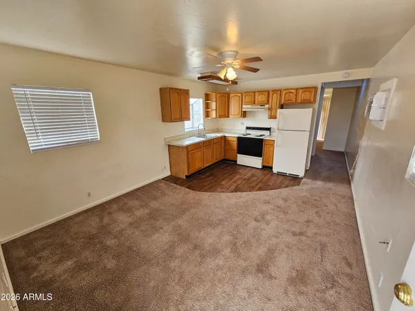 a large white kitchen with a stove a sink dishwasher and a refrigerator with wooden floor