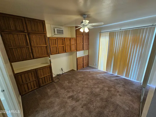 a view of an empty room with wooden floor and fan