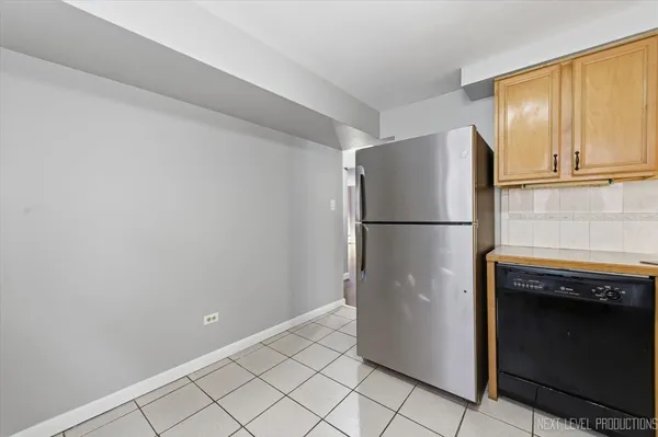 a view of a refrigerator in kitchen and an empty room with wooden floor