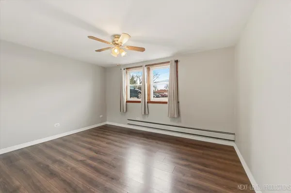 an empty room with wooden floor fan and windows