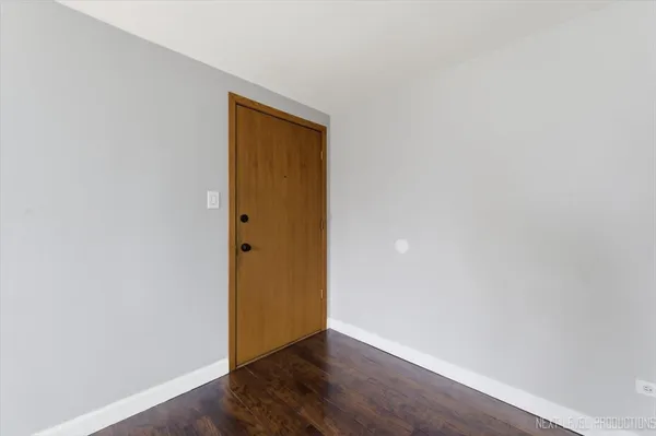 a view of an empty room with wooden floor and closet
