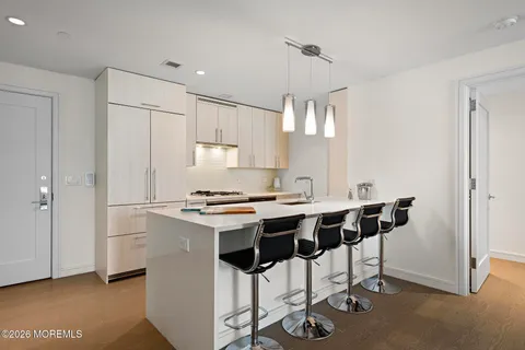 a kitchen with stainless steel appliances a stove a sink refrigerator and white cabinets with wooden floor