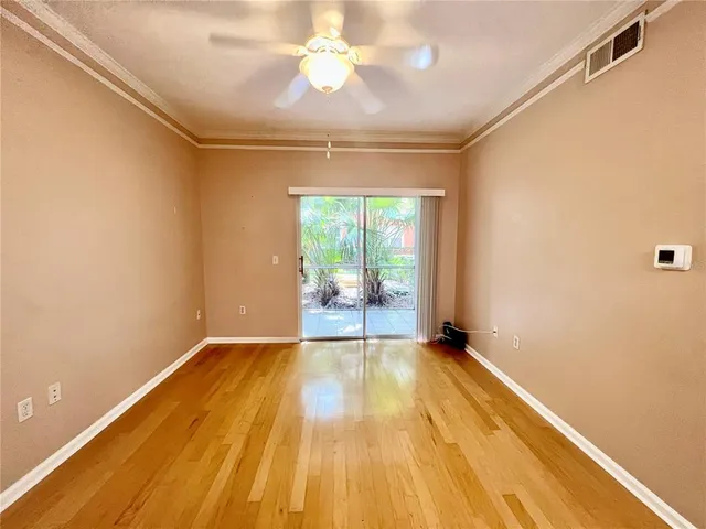 a view of empty room with wooden floor and fan