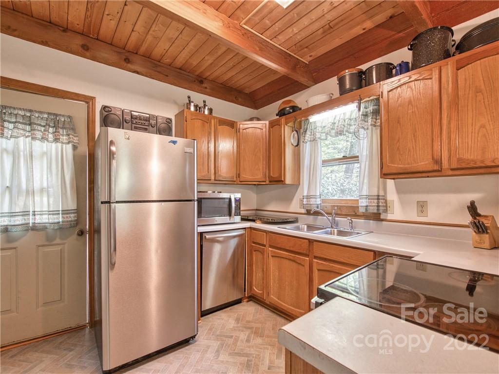86 Confederate Road Clyde, NC 28721 - Photo 11 of 26 a kitchen with stainless steel appliances granite countertop a refrigerator a sink dishwasher a stove with white cabinets and wooden floor